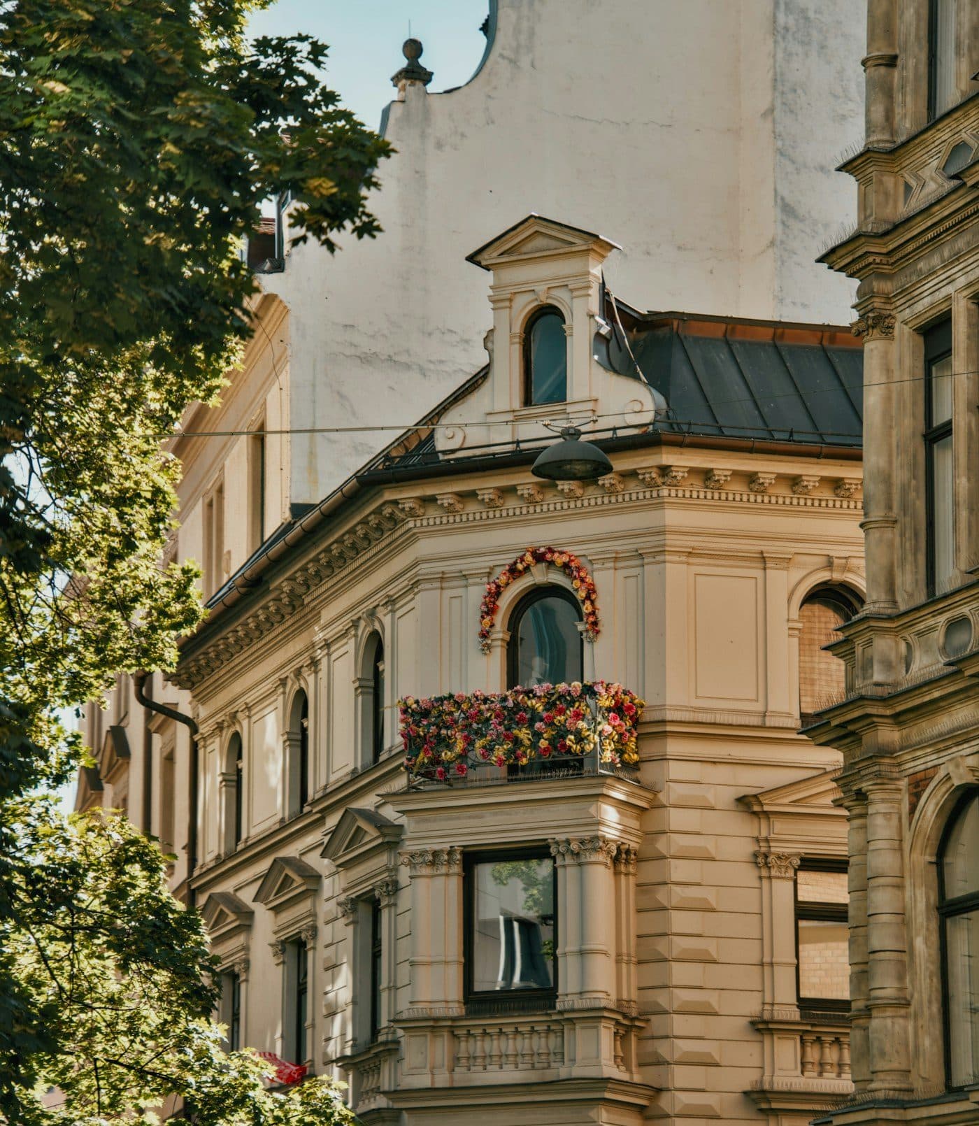 BEISPIEL-FOTO: Münchner Eckhaus mit Blumenbalkon und Bäumen